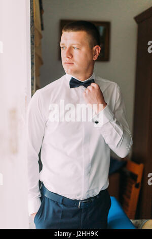 Portrait of elegant young fashion groom in white shirt and bow-tie. Stock Photo