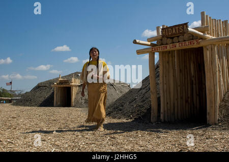 Women of the Mandan, Hidatsa and Arikara built permanent earthen lodges that formed large communities along the Missouri River. A woman presenter in traditional dress explains at the re-constructed Indian village on the Fort Berthold Reservation, ND Stock Photo