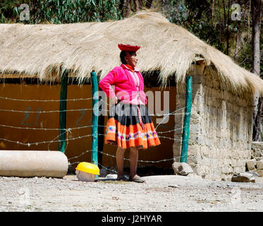 Quechua woman dressed in colourful traditional handmade outfit, standing by barbed wire fence. October 21, 2012 - Patachancha, Cuzco, Peru Stock Photo