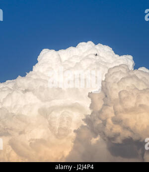 Storm clouds and a distant airplane. Early evening sky at sunset. Stock Photo