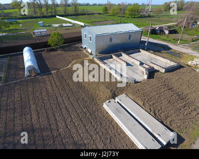 Buildings on the site. Hangar from metal profile, corrugated. The foundation of the house Stock Photo