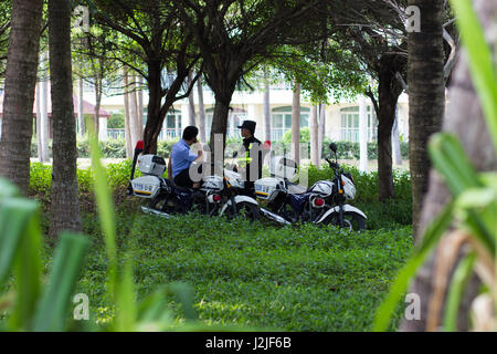 Sanya, China April 23, 2017 - Chinese policemen on motorcycles stand in a coastal avenue located on the shore of the South China Sea in Sanya Bay, Hai Stock Photo