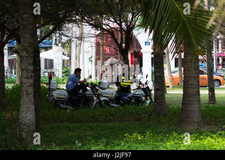 Sanya, China April 23, 2017 - Chinese policemen on motorcycles stand in a coastal avenue located on the shore of the South China Sea in Sanya Bay, Hai Stock Photo