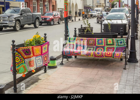 Colorful, knitted coverings for a bench and planter in PUNTA ARENAS, CHILE - NOVEMBER 2015. Stock Photo