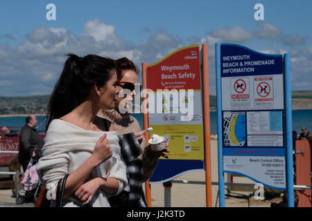 Weymouth, Dorset, UK. 29th Apr, 2017. Two Young women enjoy an icecream by the beach and make the best or a cool and breezy day with occasional spells of sunshine at Weymouth as the weather is set to deteriorate tomorrow with rain moving into the area. Credit: Tom Corban/Alamy Live News Stock Photo