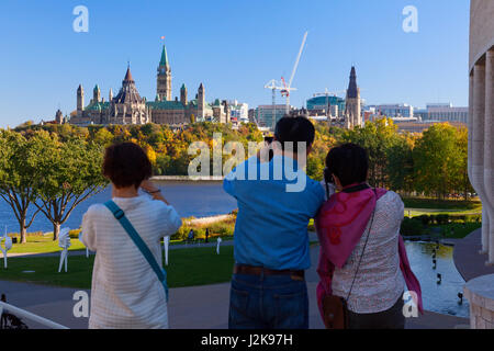 Parliament Hill in Ottawa, Ontario with tourists in the foreground taking pictures as seen from Hull, Gatineau, Quebec, Canada. Stock Photo