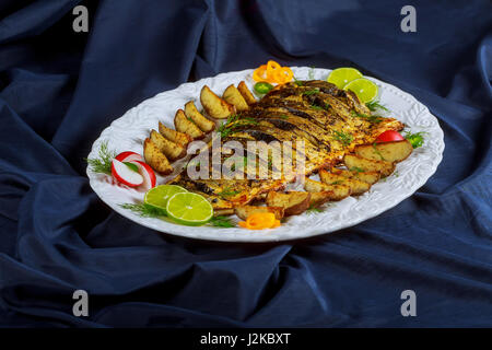 Grilled trout, served with lemon and decorated baked fish with potatoes in the oven Stock Photo