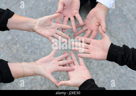 Overhead view of three friends and their hands in a circle with palms facing upwards Stock Photo