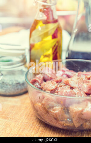 Raw pork neck meat cut in slices with marinated in glass bowl  in a modern kitchen. Shallow depth of field. Toned Stock Photo