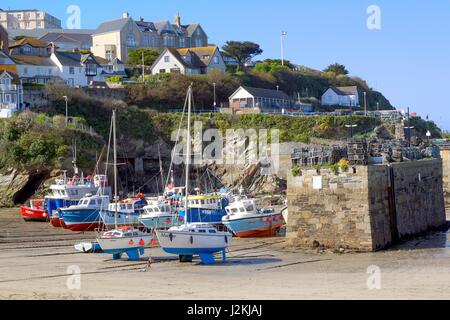 Newquay, Cornwall, UK - April 1 2017: Colourful fishing and sailing boats on the sand in Newquay harbour at low tide, lobster pots on the quay, houses Stock Photo