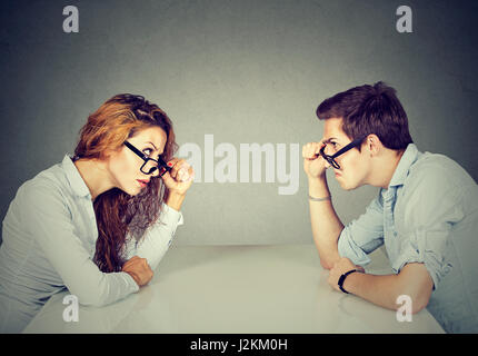 Angry man and woman sitting at table looking at each other with hatred and disgust Stock Photo