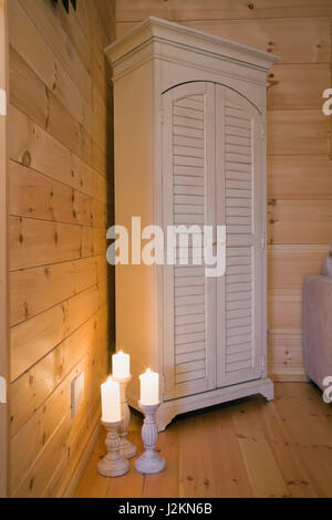 Antique wooden armoire and lit candles on the mezzanine inside a small cottage style log home Stock Photo