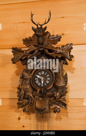 Close-up brown wooden cuckoo clock on pinewood wall inside a small cottage style log home Stock Photo