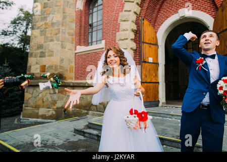 Jubilant bride and groom leaving the church after a wedding ceremony Stock Photo