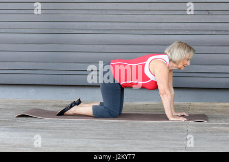 Senior woman doing fitness exercises on a gym mat to strengthen her muscles Stock Photo