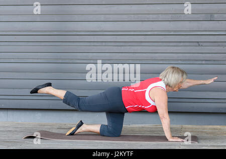Senior woman doing fitness exercises on a gym mat raising her feet in the air to strengthen her abdominal muscles Stock Photo