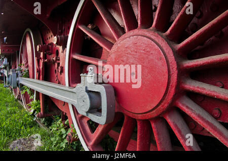 Red wheels of big old steam locomotive from Orient Express, in front of a factory where it has been produced Stock Photo