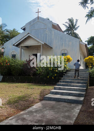 TODAK ISLAND, BATAM, INDONESIA. A boy steps up the stairs in front of a white wall church. Stock Photo