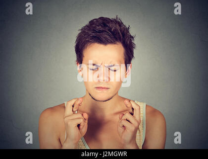 Closeup portrait of young guy, man crossing fingers, wishing, hoping isolated on gray background. Human emotion facial expression feeling attitude Stock Photo