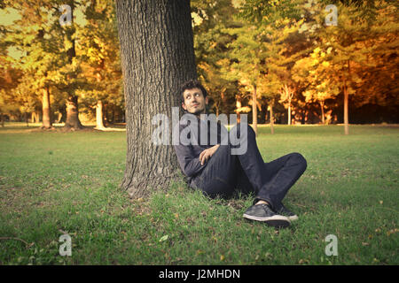 Young man sitting under tree Stock Photo