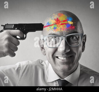Businessman holding gun to his head, colorful paint on head Stock Photo