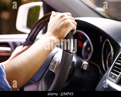 hands of a male driver holding steering wheel of a vehicle, close-up. Stock Photo