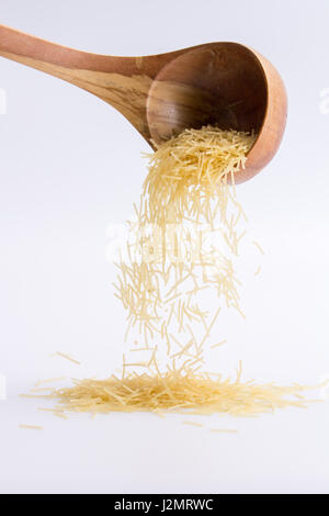 Raw pasta filini on a white background, falling from a wooden spoon. isolated Stock Photo