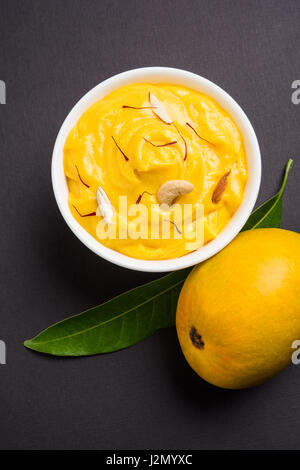 hapus or alphonso Mango pudding / Mango shrikhand or srikhand or amrakhand - Mango dessert with condensed milk magoes and nuts, selective focus over w Stock Photo