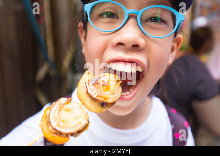 Happy asian girl about to eat skewer scallops at Tsukiji, Tokyo Fish Market Stock Photo