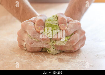 A man makes spinach pasta for ravioli. The process of kneading the dough. Stock Photo