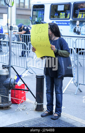 A woman holds up a sign in New York city on September 12, 2010 at protests for and against a mosque at ground zero that says God Forgive America Stock Photo