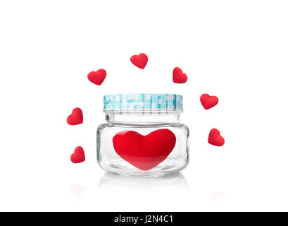 valentine and love theme, big red felt heart in glass jar with blue poka dot lid surrounded by small red hearts, isolated white background Stock Photo