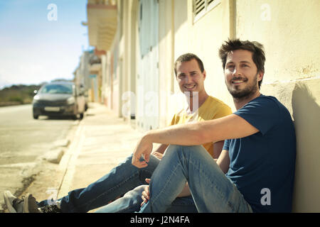 2 men sitting on the streets Stock Photo