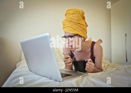 Surprised woman in towel laying on bed Stock Photo