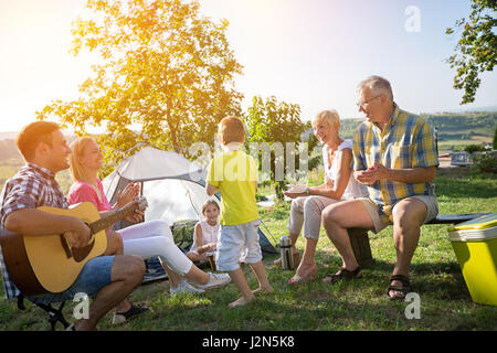 happy family and children enjoying with guitar in a tent Stock Photo