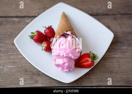 strawberry ice cream in waffle cone on the plate
