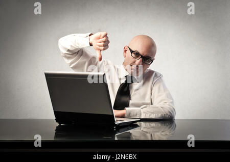 Unhappy bald businessman working on laptop Stock Photo