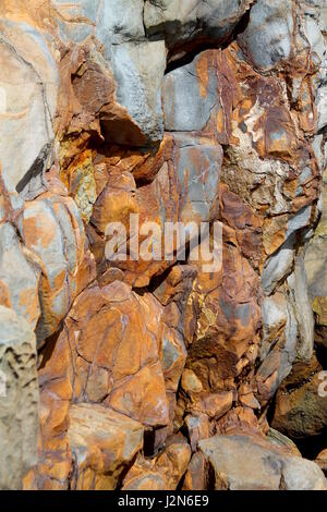 Rust colored rocks on sea cliff Stock Photo