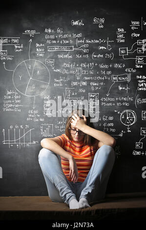 Depressed woman in front of chalkboard with notes Stock Photo