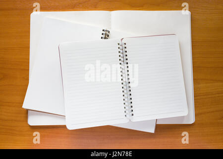 Stack of three empty white notebooks on wooden desk Stock Photo