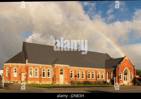 Rainbow over a big brick church in Masterton New Zealand. Stock Photo