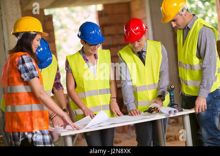 Architect explaining his idea on plan to group of workers Stock Photo