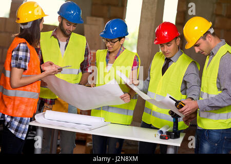Group of architects and construction workers on site with blue print Stock Photo