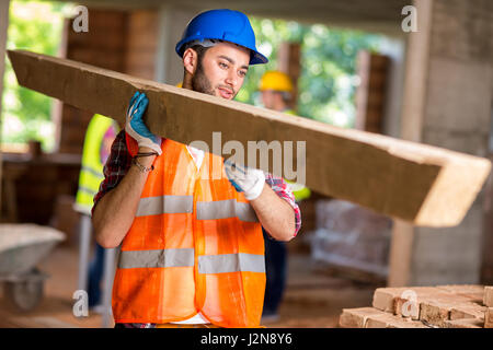 Young worker bring construction timber at work Stock Photo