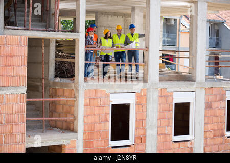 Side view of construction in progress with group of architects monitoring construction Stock Photo