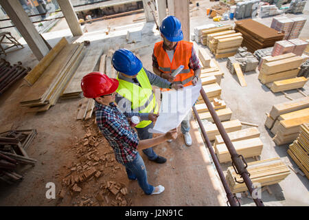 Construction engineers checking blue print at building place Stock Photo