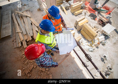 Top view of young workers checking blue print at building place Stock Photo