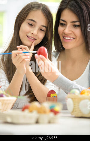 Smiling mother  painting Easter eggs with daughter Stock Photo