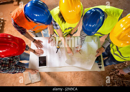 Top view of group of architects and engineers checking blue print if construction is going as planned Stock Photo