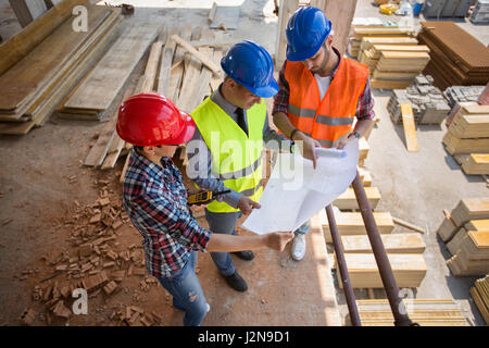 Architects consulting each other about construction plan surrounded by materials Stock Photo